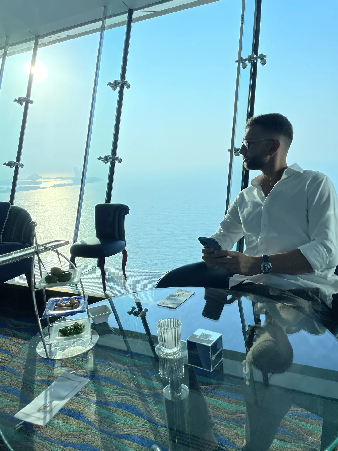 Albert Prediger in Hochhaus-Lounge mit Meerblick, weißes Hemd, Telefon in der Hand